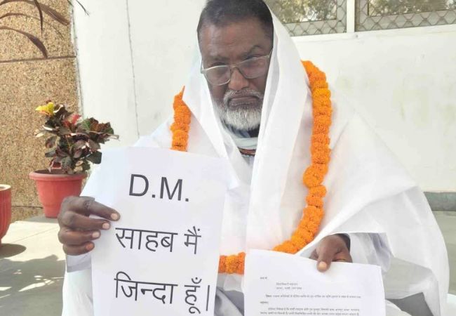 सरकारी फाइलों में मुर्दा है रिटायर्ड कर्मचारी, कफन ओढ़कर खुद को जिंदा साबित करने पहुंचा DM कार्यालय